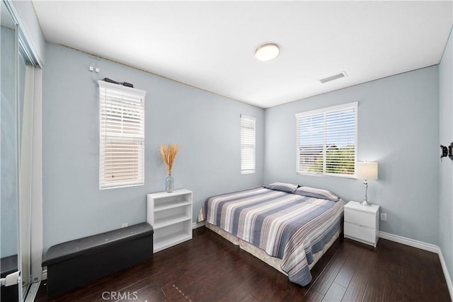 bedroom with dark wood-style floors, baseboards, and visible vents