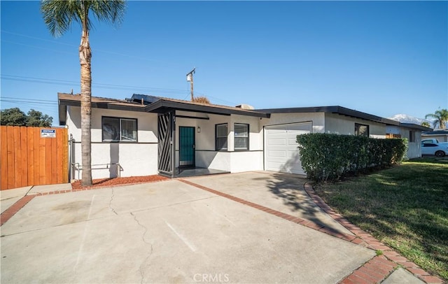 view of front of property featuring a garage, driveway, a front lawn, and stucco siding