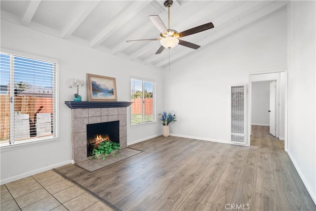 unfurnished living room featuring ceiling fan, light wood-style flooring, a fireplace, baseboards, and beam ceiling