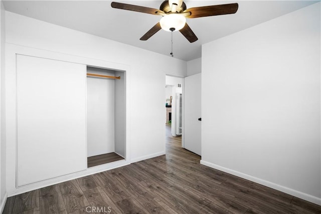 unfurnished bedroom with dark wood-style floors, a closet, a ceiling fan, and baseboards