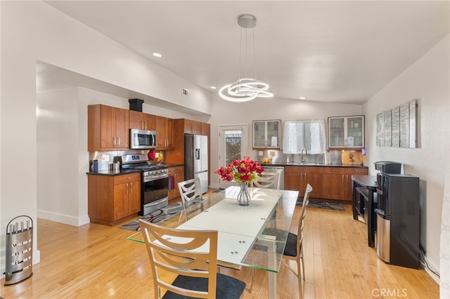 kitchen with lofted ceiling, light wood finished floors, appliances with stainless steel finishes, and a sink