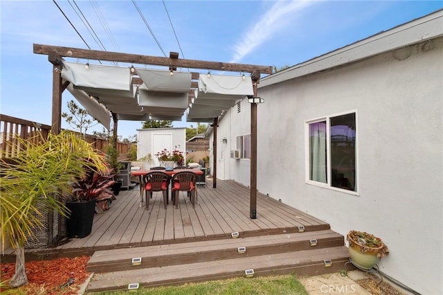 deck with a storage shed, fence, an outbuilding, and outdoor dining space