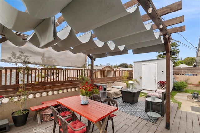 wooden terrace with a shed, outdoor dining area, an outdoor structure, and fence