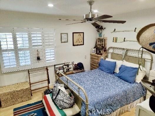 bedroom featuring ceiling fan, multiple windows, and wood finished floors