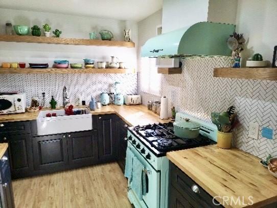 kitchen with a sink, open shelves, exhaust hood, and white range with gas cooktop