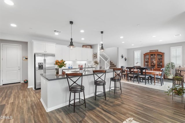 kitchen with visible vents, white cabinetry, hanging light fixtures, dark countertops, and stainless steel fridge