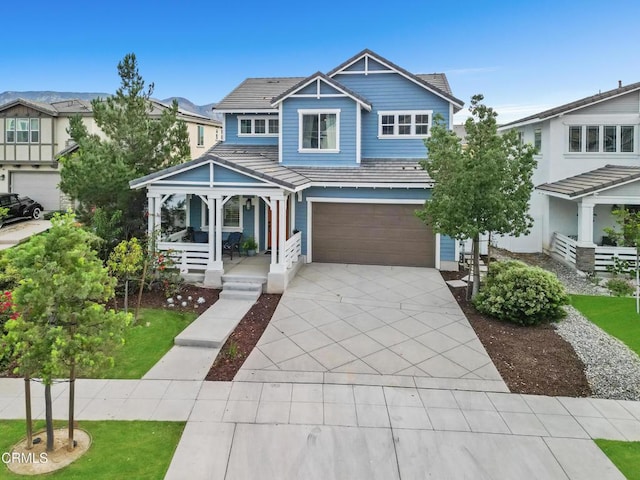 view of front of house featuring driveway, a garage, a tile roof, a residential view, and a porch