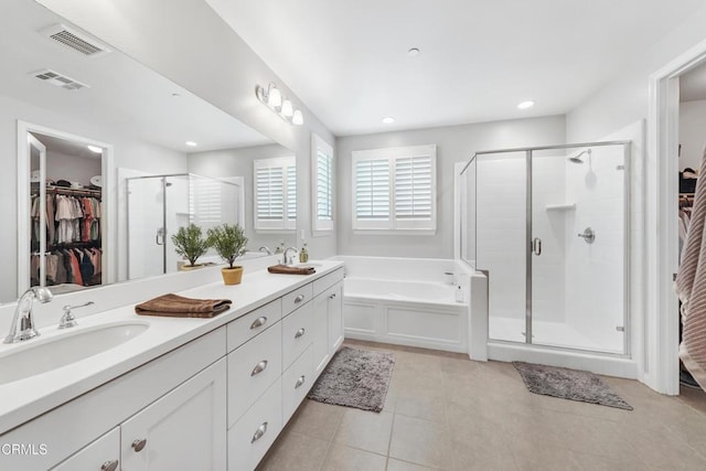 full bath featuring a stall shower, visible vents, tile patterned floors, a walk in closet, and a sink