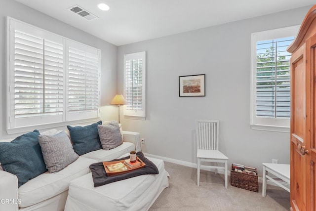 living area with light carpet, baseboards, and visible vents