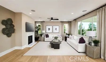 living area with recessed lighting, light wood-style floors, a glass covered fireplace, a ceiling fan, and baseboards