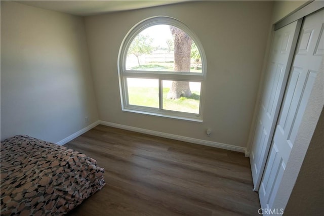 bedroom with a closet, wood finished floors, and baseboards