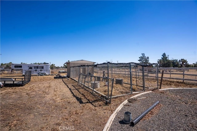 view of yard featuring fence, an outbuilding, and a rural view