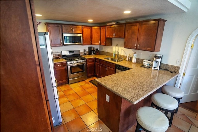 kitchen with a breakfast bar area, recessed lighting, appliances with stainless steel finishes, a sink, and a peninsula