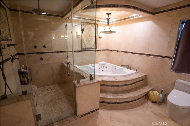 bathroom featuring toilet, a jetted tub, a shower stall, and tile walls