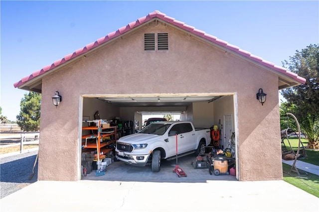 garage with concrete driveway and fence