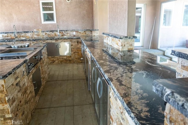 kitchen with stainless steel gas stovetop and dark stone countertops