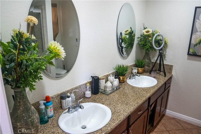 full bathroom with double vanity, baseboards, a sink, and tile patterned floors