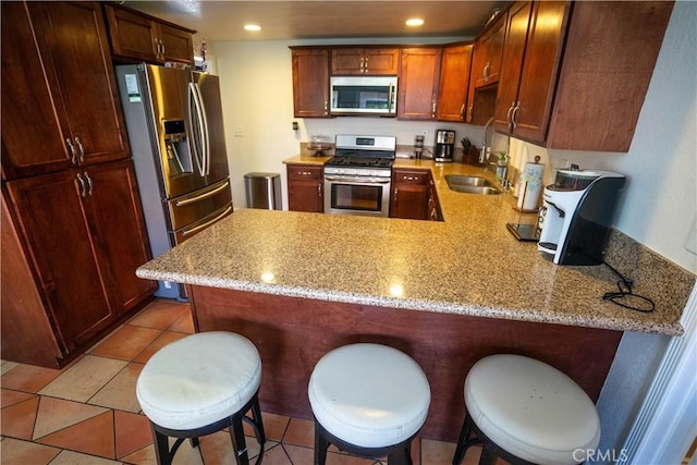 kitchen featuring a peninsula, appliances with stainless steel finishes, a kitchen breakfast bar, and recessed lighting