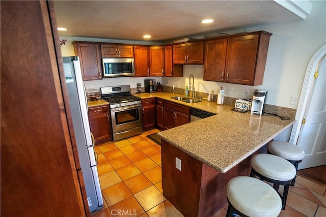 kitchen with recessed lighting, stainless steel appliances, a breakfast bar, a peninsula, and a sink