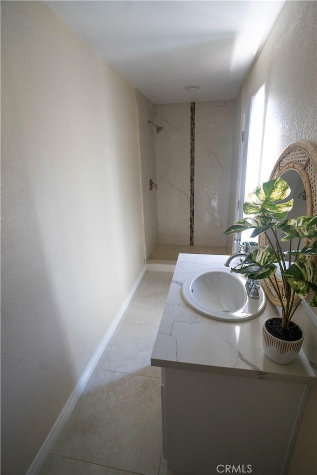 full bath featuring vanity, baseboards, and walk in shower