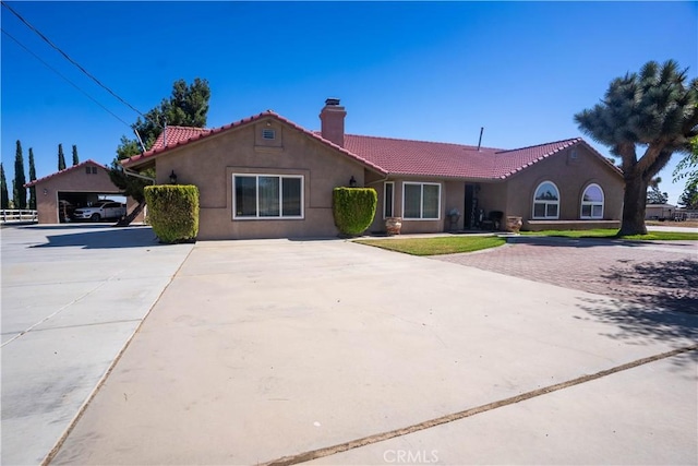 view of front of property with an outbuilding, a chimney, a tiled roof, and stucco siding