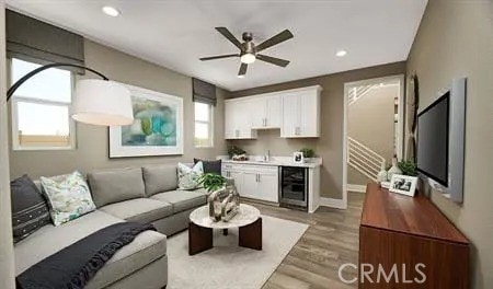 living room with wine cooler, recessed lighting, ceiling fan, light wood-type flooring, and stairs
