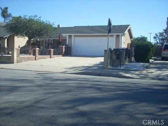 single story home featuring concrete driveway, fence, an attached garage, and stucco siding