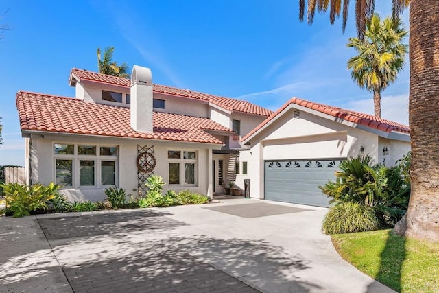 mediterranean / spanish house featuring an attached garage, driveway, a tile roof, and stucco siding