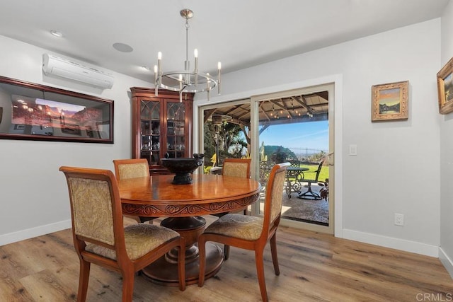 dining area with a chandelier, a wall mounted AC, wood finished floors, and baseboards