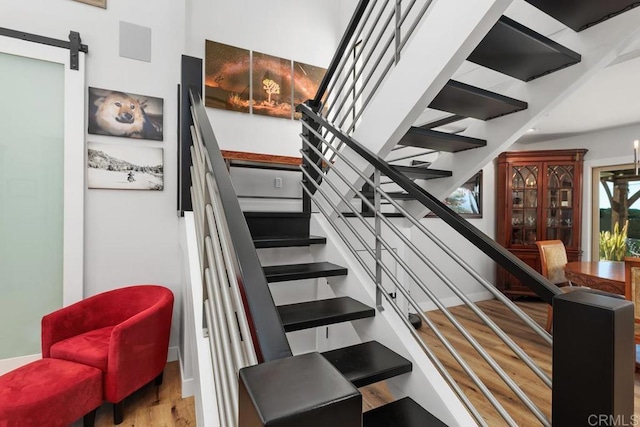 staircase featuring a barn door and wood finished floors