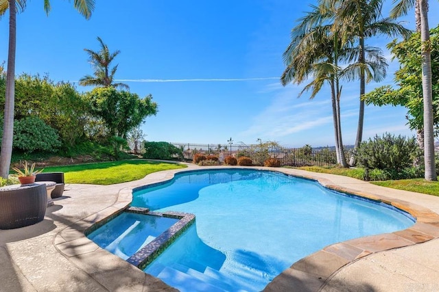 view of pool featuring a lawn, fence, and a pool with connected hot tub