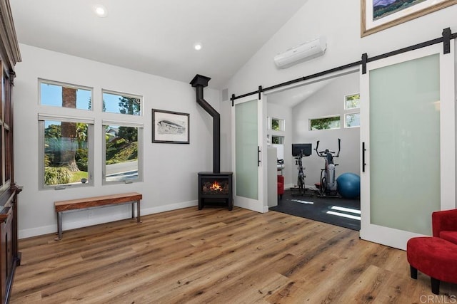 exercise area with wood finished floors, a wall mounted air conditioner, plenty of natural light, and a barn door