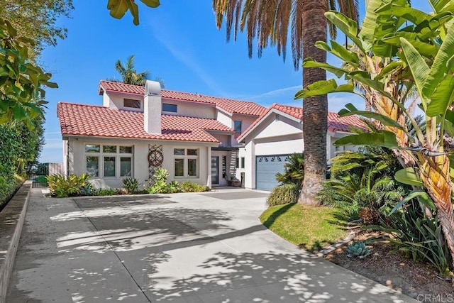 mediterranean / spanish house featuring a garage, a tile roof, concrete driveway, and stucco siding