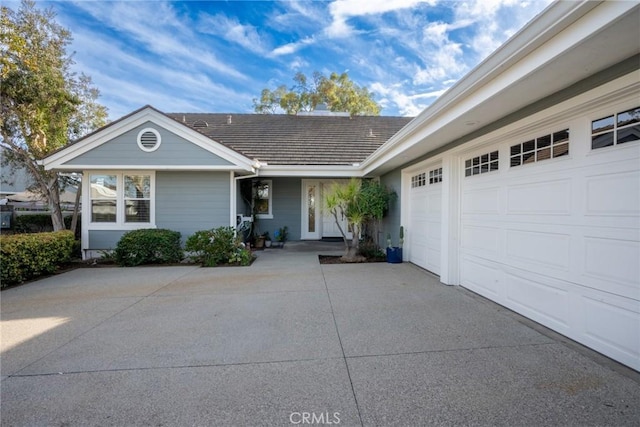 view of front of property featuring a garage, a tile roof, and driveway