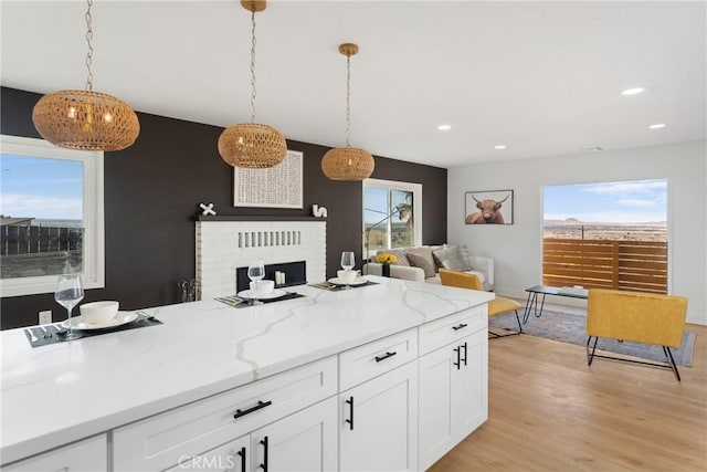 kitchen with hanging light fixtures, a wealth of natural light, white cabinetry, and light wood-style floors