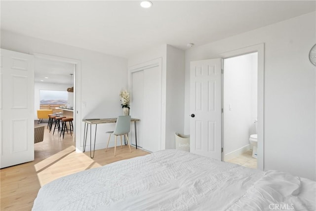 bedroom with baseboards, wood finished floors, ensuite bathroom, a closet, and recessed lighting