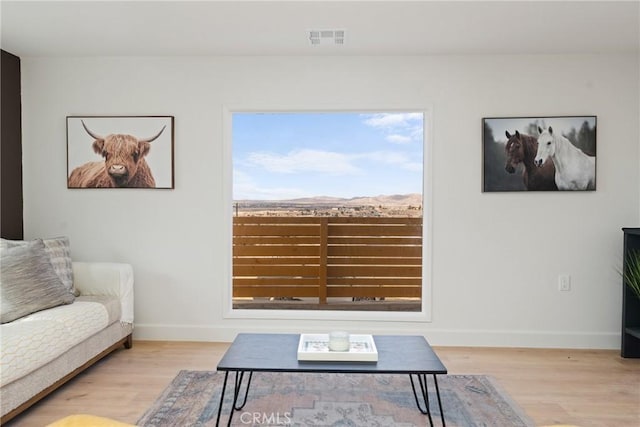 living area with wood finished floors, visible vents, and baseboards