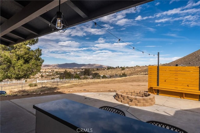 exterior space featuring an outdoor fire pit, a mountain view, a patio, and fence