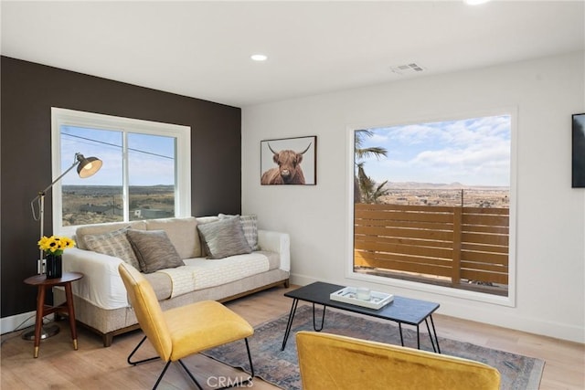 living area with recessed lighting, wood finished floors, visible vents, and baseboards