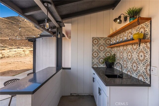 kitchen featuring dark countertops, white cabinetry, a sink, and open shelves