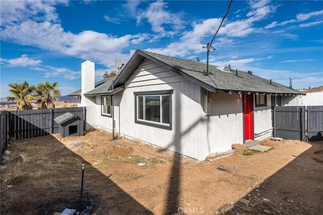 view of property exterior featuring a fenced backyard, a chimney, and roof with shingles