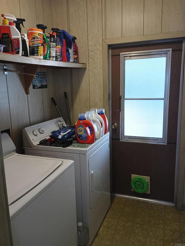 laundry area featuring dark floors, laundry area, independent washer and dryer, and wood walls