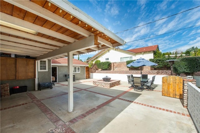 view of patio / terrace with a fire pit, outdoor dining space, and fence