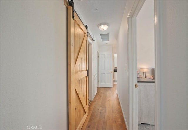 corridor featuring light wood-style floors and a barn door