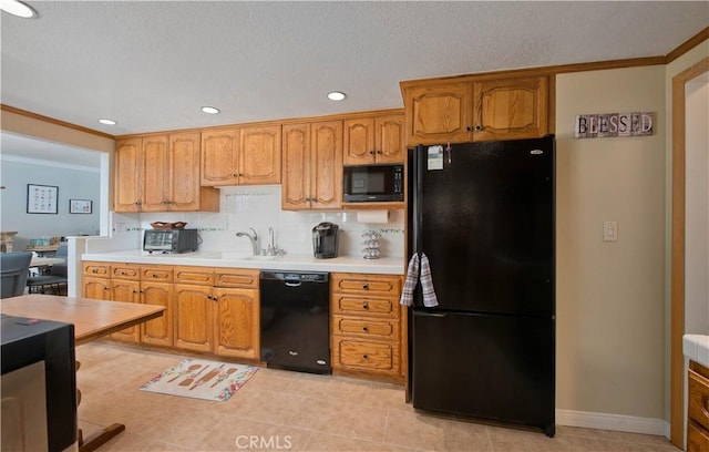 kitchen with a sink, light countertops, ornamental molding, black appliances, and brown cabinetry