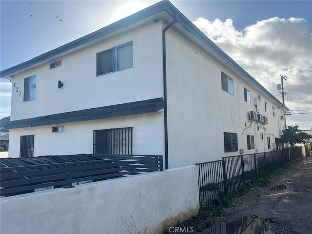 view of property exterior with fence and stucco siding