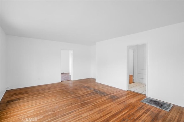 empty room featuring wood finished floors and visible vents