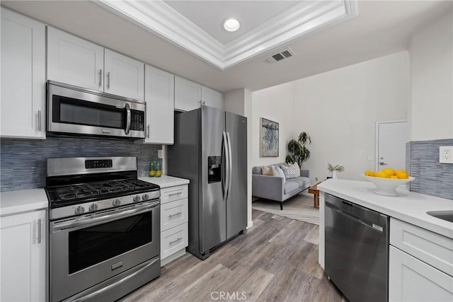 kitchen featuring visible vents, white cabinets, appliances with stainless steel finishes, a tray ceiling, and light countertops