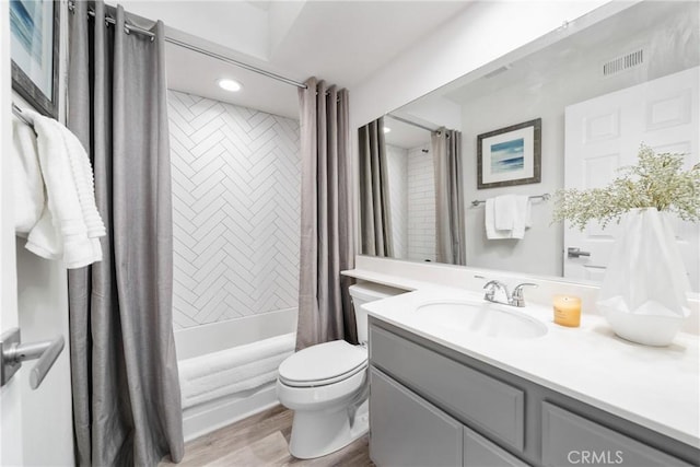 full bathroom featuring toilet, wood finished floors, visible vents, vanity, and shower / bathtub combination with curtain