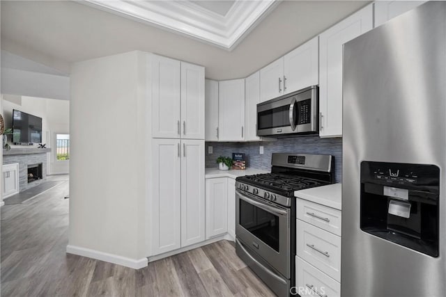 kitchen featuring white cabinetry, light countertops, ornamental molding, appliances with stainless steel finishes, and decorative backsplash